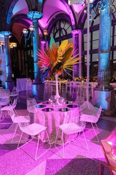 the tables and chairs are all set up for a party or function with purple lighting