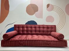 a red couch sitting in front of a wall with colorful circles on it's walls