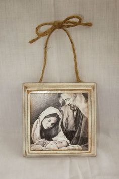 an old photo hanging from a string on a white cloth covered wall with twine