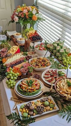 a table filled with lots of different types of food on top of plates and trays