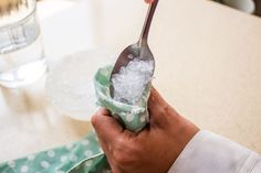 a person holding a spoon with ice on it