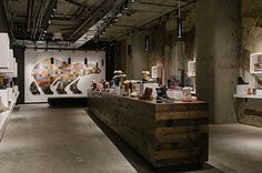 the interior of an art gallery with various items on shelves and artwork hanging from the ceiling