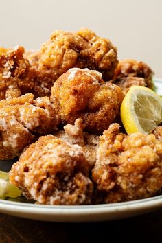 fried food on a plate with lemon wedges