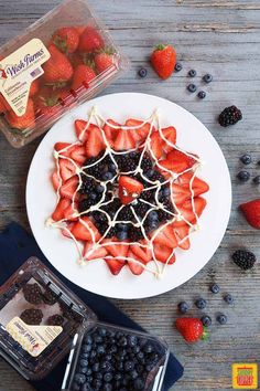 a white plate topped with strawberries and blueberries next to a container of berries