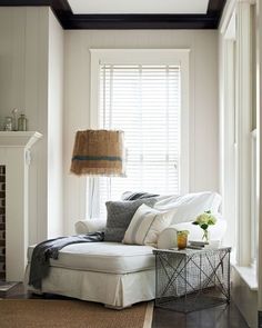 a living room with white furniture and pillows on the couch in front of a window