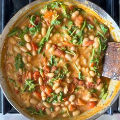 a pot filled with beans and greens on top of a stove