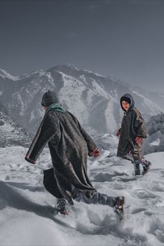 two people walking in the snow on top of a mountain with their feet covered by snow