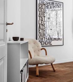 a chair sitting in front of a white wall next to a book shelf with books on it