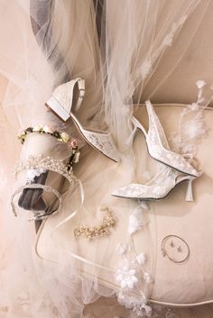 wedding shoes and jewelry laid out on a white cloth with veil over them, sitting on top of a chair