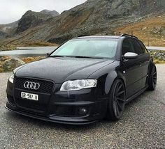 the black car is parked on the side of the road in front of some mountains