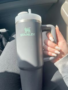 a woman is holding a cup in her hand while sitting in the back seat of a car