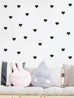 two stuffed animals sitting on top of a couch in front of a wall with hearts