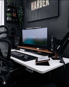 a desk with a computer monitor, speakers and other items on it in front of a black wall