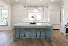 a large kitchen with white cabinets and an island in the middle, along with hardwood flooring