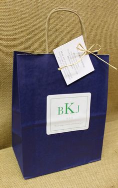 a blue paper bag with a label on it sitting on a couch next to a pillow