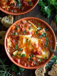 two bowls of pasta soup with bread and parsley