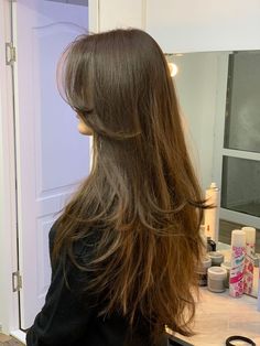 a woman with long hair standing in front of a mirror