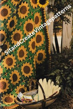 a crocheted blanket with sunflowers on it next to a basket full of gardening utensils