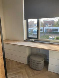 an empty desk in front of a large window with a view of the street outside