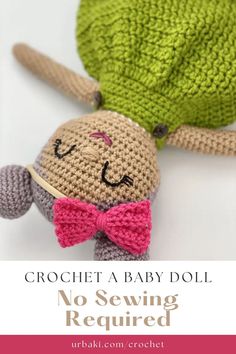 a crochet baby doll with a pink bow tie laying on top of it