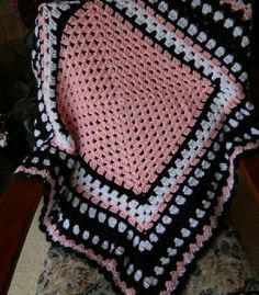 a crocheted blanket sitting on top of a chair next to a flower pot