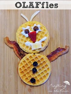 two waffles with faces made out of bacon and other ingredients on a wooden surface