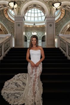 a woman in a white dress standing on some stairs