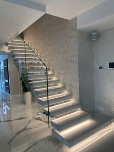 the stairs are lit up with leds in this modern style home interior design, which features white marble floors and handrails