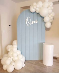 balloon arch with white balloons in front of it and one sign on the back wall