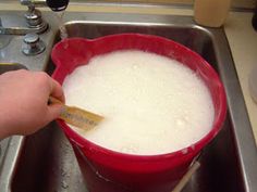 a red bowl filled with liquid sitting on top of a kitchen sink