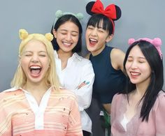 four young women are posing for a photo with mickey mouse ears on their heads and one is laughing