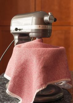 a kitchen mixer with a pink cover on it's top sitting on a counter