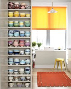 the shelves in the kitchen are filled with bowls and plates, along with a rug