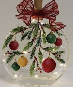 a glass ornament with christmas decorations on it and a red bow hanging from the top