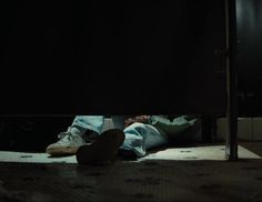 a person laying on the ground with their feet up in front of a black wall