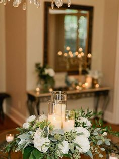 a centerpiece with candles, flowers and greenery