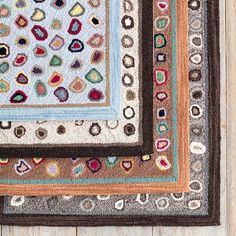 a multicolored area rug on a wooden floor with white wood boards in the background