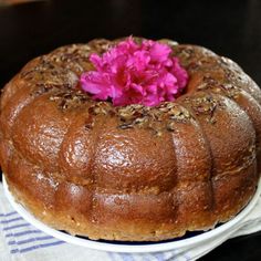 a bundt cake sitting on top of a white plate next to a pink flower