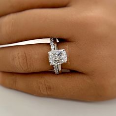 a woman's hand with a diamond ring on top of her finger and an engagement band