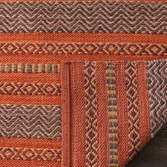 an orange and brown rug on top of a wooden floor