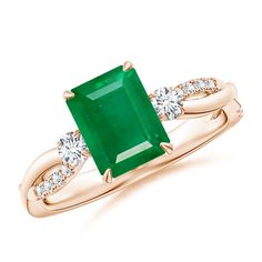 an emerald and diamond ring with two diamonds on the band, set in yellow gold