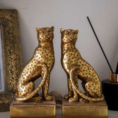 two gold cheetah figurines sitting next to each other on a table