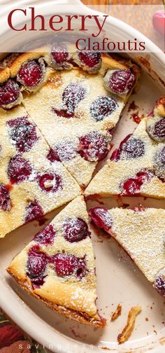 a pie with cherries and powdered sugar on top sits in a white casserole dish