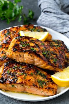 grilled salmon with lemon wedges and parsley on a white plate, ready to be eaten