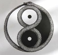 a black and white yin - yang symbol is hanging from a string on a wall