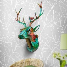 a deer head mounted to the side of a wall next to a vase and lamp