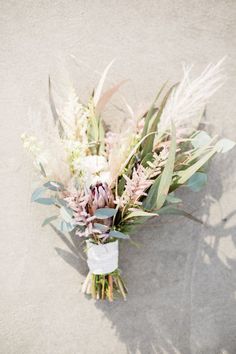 a bouquet of flowers and greenery is laying on the ground with no one around it