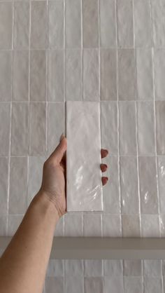 a hand is holding a piece of white tile