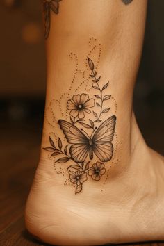 a woman's foot with a butterfly and flowers tattoo on the side of her leg