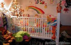 a baby crib with stuffed animals and other toys in it next to a rainbow - themed wall